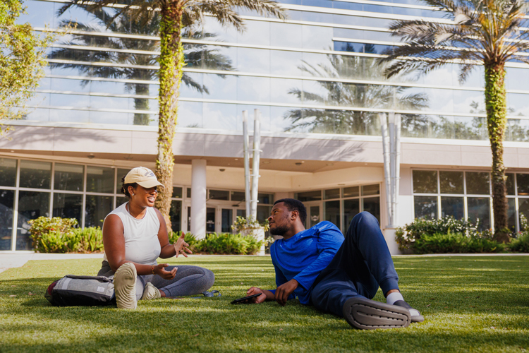 University classmates speaking on campus lawn