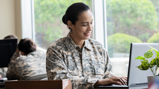 Woman in military uniform using a laptop in an office