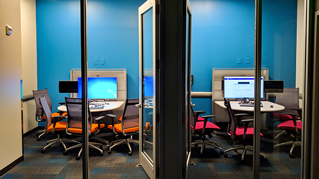 Shark tank office with large monitors and a table with chairs