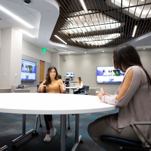 two students sitting at a round table having a discussion 